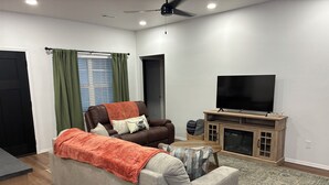 Un salon avec un canapé, un téléviseur et un meuble.