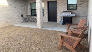 Une terrasse extérieure équipée d’un barbecue, de chaises pliantes et d’une table.