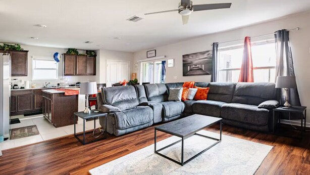 A modern living room with a grey sectional sofa, a coffee table, and a ceiling fan. - Spacious 4 bedroom house in charming Wesley Chapel with AC (Wesley Chapel)