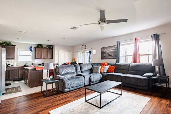 A modern living room with a grey sectional sofa, a coffee table, and a ceiling fan. - Spacious 4 bedroom house in charming Wesley Chapel with AC (Wesley Chapel)