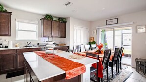 Una cocina moderna con armarios de madera oscura, una isla blanca y una zona de comedor con mantel individual rojo.