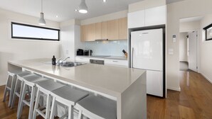 Cozinha moderna com ilha central, banquetas e uma grande janela.