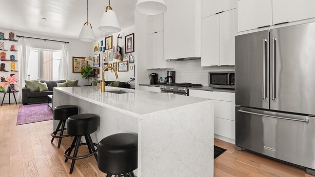 A modern kitchen with a large island, stainless steel appliances, and pendant lighting.