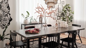 A modern dining area with a dark wooden table, black chairs, and a decorative centerpiece.