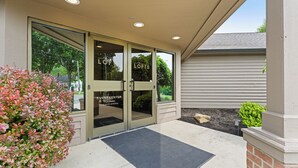 A building entrance with glass doors, a black mat, and a sign reading 'The Lofts Pub Dining.' - Birdie Suite by The Inn & Spa at Cedar Falls (Logan)