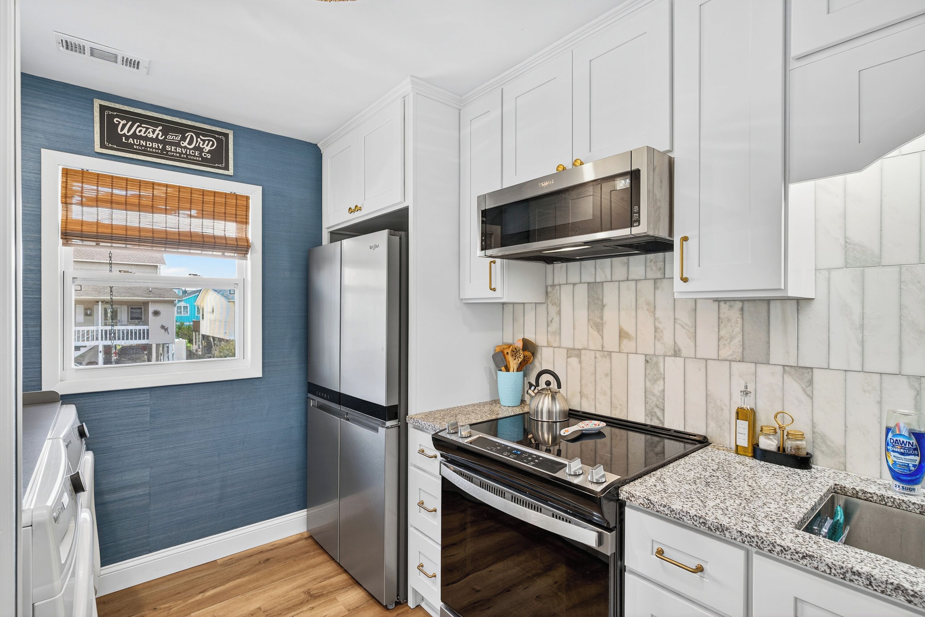 Una cocina moderna con armarios blancos, electrodomésticos de acero inoxidable y una pared de acento azul.
