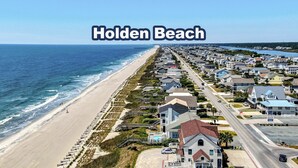 Una zona residencial costera con playa, casas y un muelle.