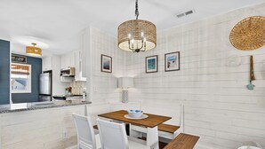 Una cocina moderna con armarios blancos, una isla de madera y un comedor con sillas blancas y una mesa de madera.