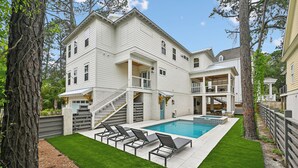 A two-story house with a swimming pool, outdoor seating, and a staircase leading to a porch. - Now Offering up to 25% OFF Fall 2026, New in 2026 , Steps to Beach, Pool, Free Golf, Dogs OK (Hilton Head Island)