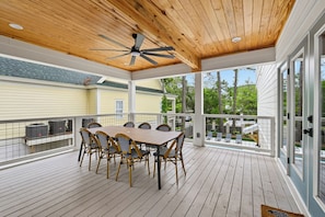 A covered outdoor deck with a table and chairs, a ceiling fan, and a view of a residential area. - New in 2026 , Steps to Beach, Private Pool, Free Golf (Hilton Head Island)