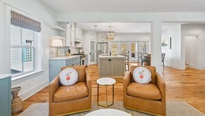 A spacious living area with two leather armchairs, a small round table, and a kitchen in the background. - Now Offering up to 25% OFF Fall 2026, New in 2026 , Steps to Beach, Pool, Free Golf, Dogs OK (Hilton Head Island)