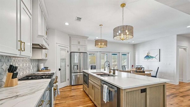A modern kitchen with white cabinetry, a large island, and a wooden floor. - Now Offering up to 25% OFF Fall 2026, New in 2026 , Steps to Beach, Pool, Free Golf, Dogs OK (Hilton Head Island)