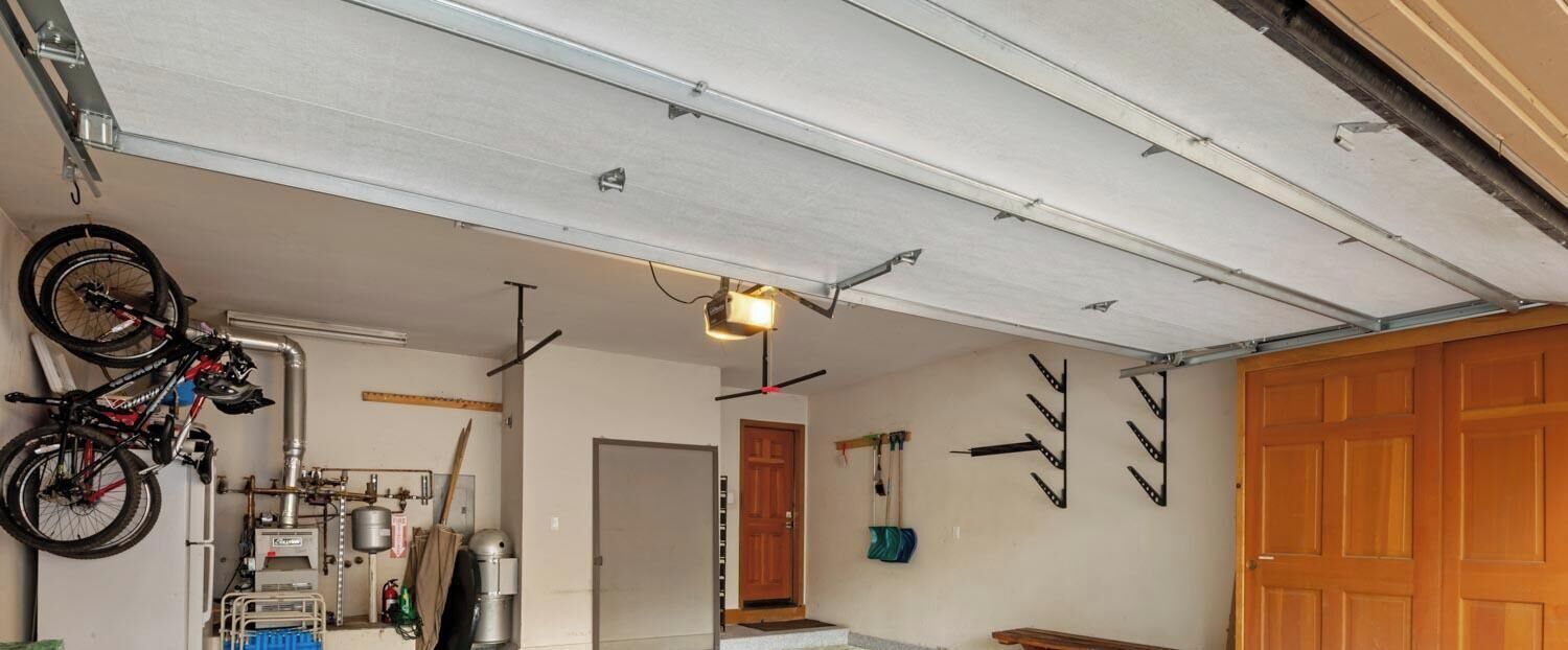 A garage with a bicycle mounted on the wall, a bench, and a door.