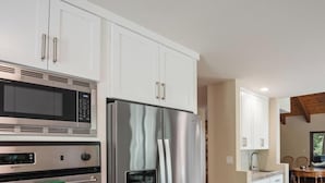 Uma cozinha moderna com eletrodomésticos de aço inoxidável, um espaço de refeições com vista e teto de madeira.