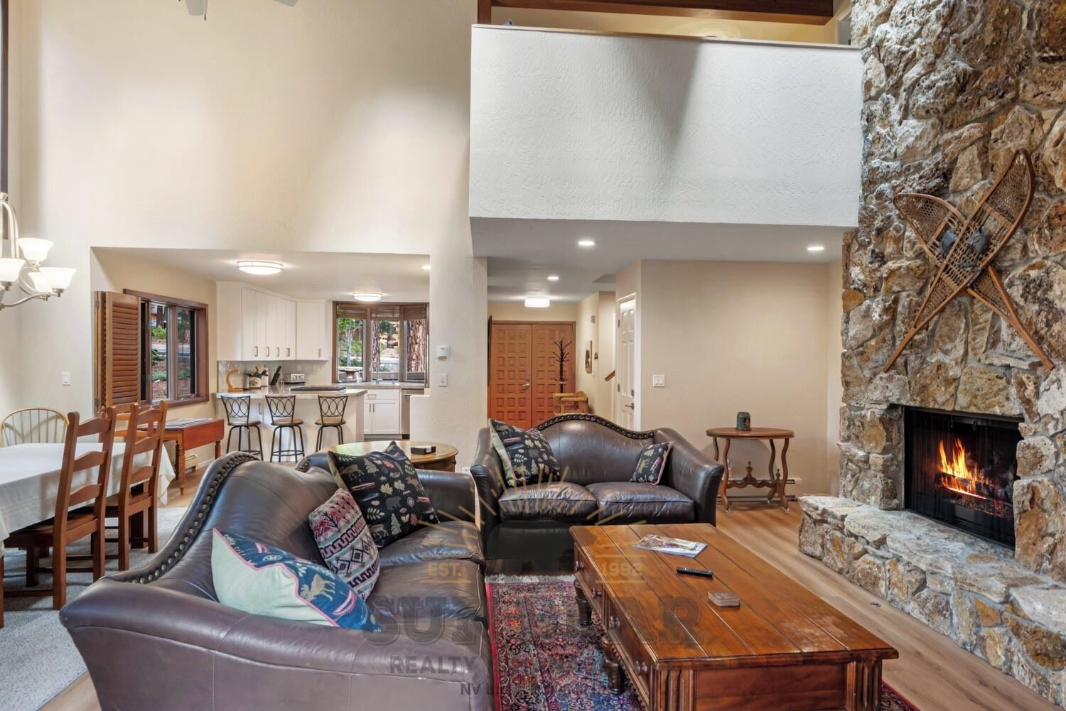 A spacious living area with a stone fireplace, leather sofas, and a dining area with wooden furniture.