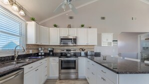 A modern kitchen with white cabinets, stainless steel appliances, and a granite countertop. - Sea Time - Corolla, Ocean Sands, Oceanside Retreat, 280 Yds to Beach, Close to Golf and Shopping (Corolla)