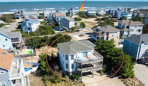 Área residencial com casas, um caminho de acesso à praia e vista para o oceano.