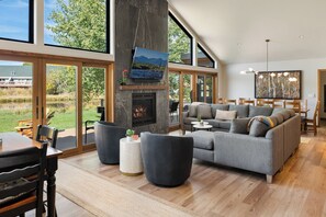 A spacious living room with a fireplace, large windows, and a dining area.
