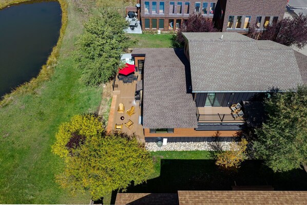 A modern house with a deck, a pond, and a grassy area.