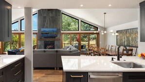 Una cocina moderna con una isla grande, armarios oscuros y una chimenea.