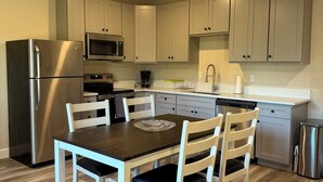 A modern kitchen with a stainless steel refrigerator, a microwave, and a dishwasher. There is a dining table with four chairs and a coffee maker on the counter. - 2 Beds / 1 bath upgraded modern lower level home in NW Portland (portland)