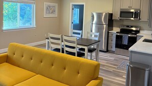 A modern kitchen with stainless steel appliances, a dining area with a yellow sofa, and a view of the outdoors through a window. - 2 Beds / 1 bath upgraded modern lower level home in NW Portland (portland)