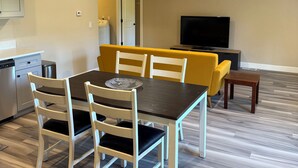 A dining area with a table and chairs, a sofa, a television, and a kitchen area with a dishwasher and stove. - 2 Beds / 1 bath upgraded modern lower level home in NW Portland (portland)