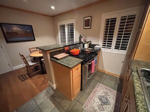Une cuisine compacte dotée d’un îlot central, d’un coin repas avec une chaise et d’une cuisinière.