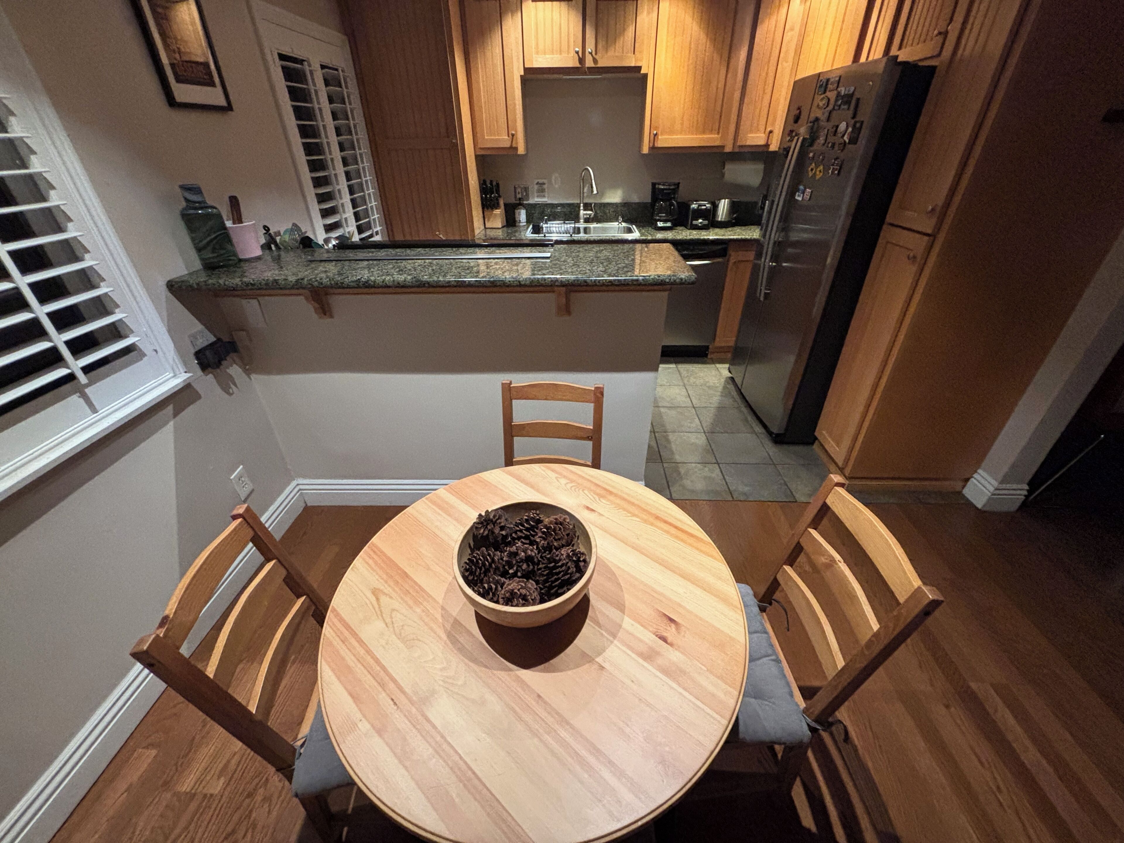 Une cuisine avec des meubles de rangement en bois, un plan de travail en granit et une table à manger avec des chaises.