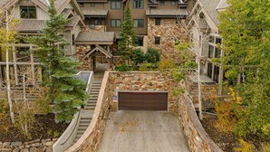 Un edificio residenziale a più piani con facciata in pietra, diversi ingressi e un vialetto che conduce a un garage.
