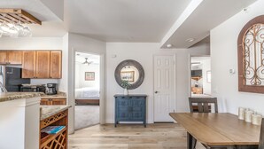 Una cocina moderna con armarios de madera, encimera de granito y comedor con mesa y sillas de madera.