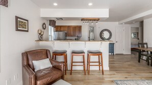 Una cocina moderna con armarios de madera, un refrigerador de acero inoxidable y una barra con taburetes.