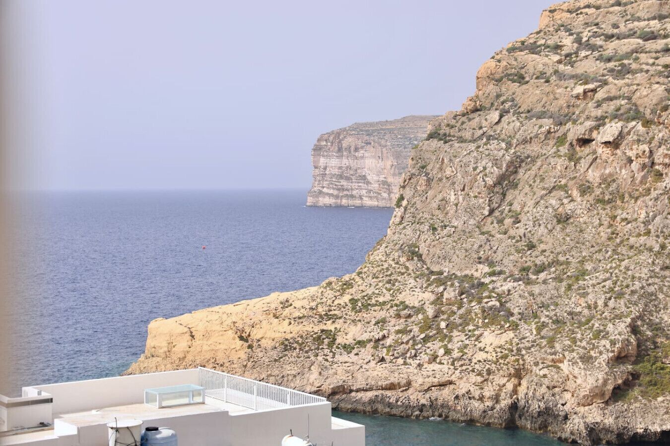 A coastal hotel with a terrace overlooking the sea and a prominent cliff.