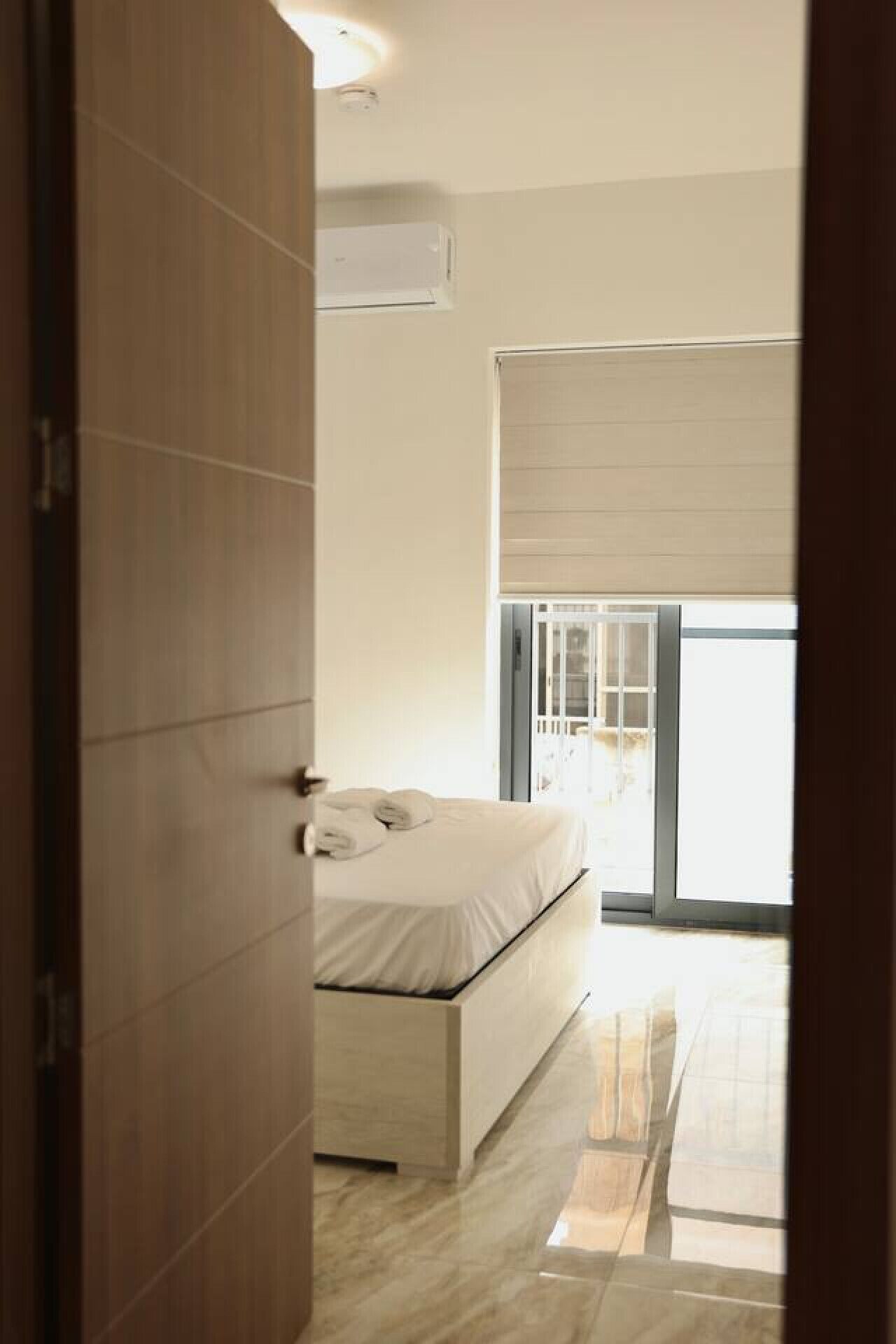 A bedroom with a bed, a wardrobe, and a sliding glass door to a balcony.