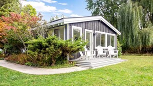 A small, modern cabin with a covered porch and white chairs. - Pet-Friendly Oasis w/ Sunroom – Steps to Beach! (Douglas)