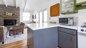 A modern kitchen with a built-in island, a microwave, and a stove. There is a grey cabinet and a green shelf above the counter. - Pet-Friendly Oasis w/ Sunroom – Steps to Beach! (Douglas)