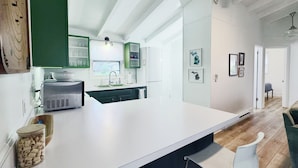 A modern kitchen with a white countertop, green cabinets, and a built-in oven. - Pet-Friendly Oasis w/ Sunroom – Steps to Beach! (Douglas)