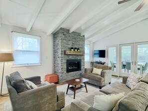Ein Wohnzimmer mit Kamin aus Stein, Sofas, einem Couchtisch und einem Fernseher.