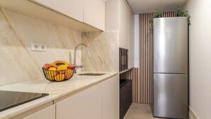 A kitchen with a marble countertop, a sink, a stainless steel refrigerator, and a fruit bowl. - Central & Cozy Studio by HostWise (Vila Nova de Gaia)