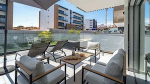 A modern balcony with outdoor seating, a table with a bottle and snacks, and a view of surrounding buildings. - Elegant Retreat with Pool & Terrace by HostWise (Alvor)