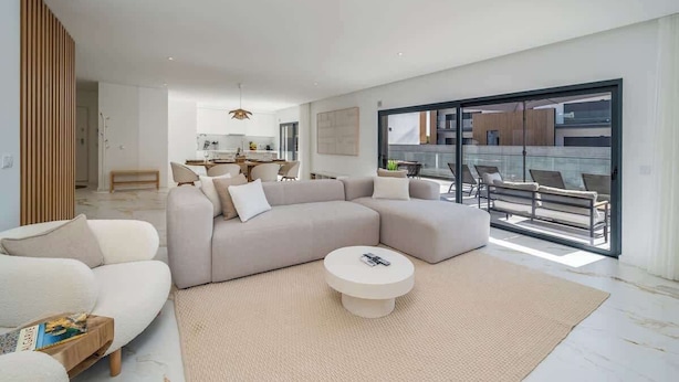 A modern living room with a large sectional sofa, a round coffee table, and a view of the outdoor balcony area. - Elegant Retreat with Pool & Terrace by HostWise (Alvor)