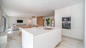 A modern kitchen with white cabinetry, a central island, and a built-in oven. - Elegant Retreat with Pool & Terrace by HostWise (Alvor)