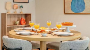 Ein Frühstückstisch gedeckt mit Tellern, Gläsern Orangensaft, einer Schüssel Müsli und einem Muffin auf einem Sockel.