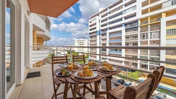 A balcony with a table set for breakfast, overlooking a residential building.