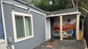 A house with a grey exterior, a white door, and a small porch with two white swing chairs. - Charming Studio in Delightful Richland (Richland)