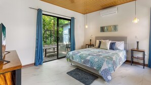 Ein Schlafzimmer mit einem großen Bett, Holzboden, einer Schiebetür zu einer Terrasse und einem Bild an der Wand.