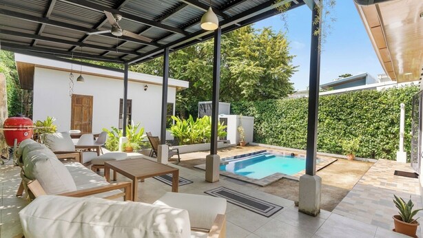 Ein überdachter Außenbereich mit Pool, Sitzgelegenheiten und Grill.