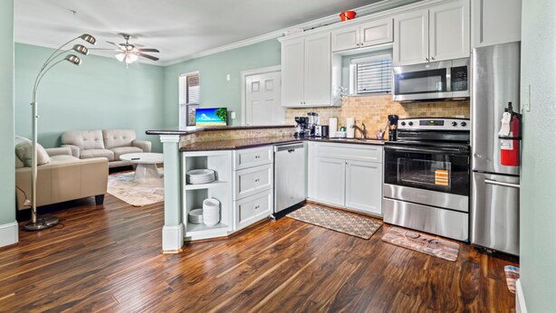 A modern kitchen with white cabinets, stainless steel appliances, and a wooden countertop. - Sunny Hidden Retreat C – Ocean Town Gem (Galveston)