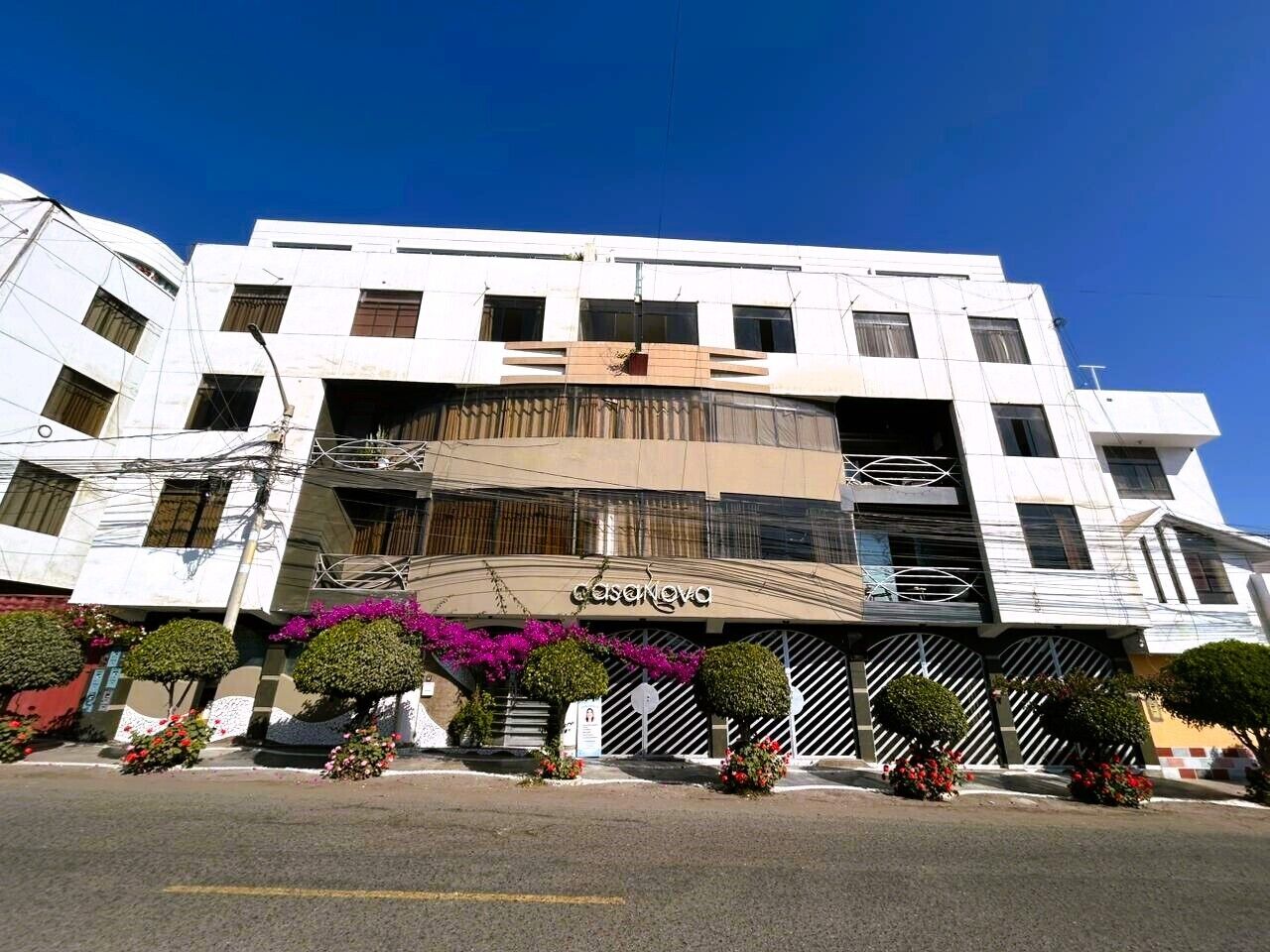 A multi-story building with a prominent entrance, balconies, and a clear sky.