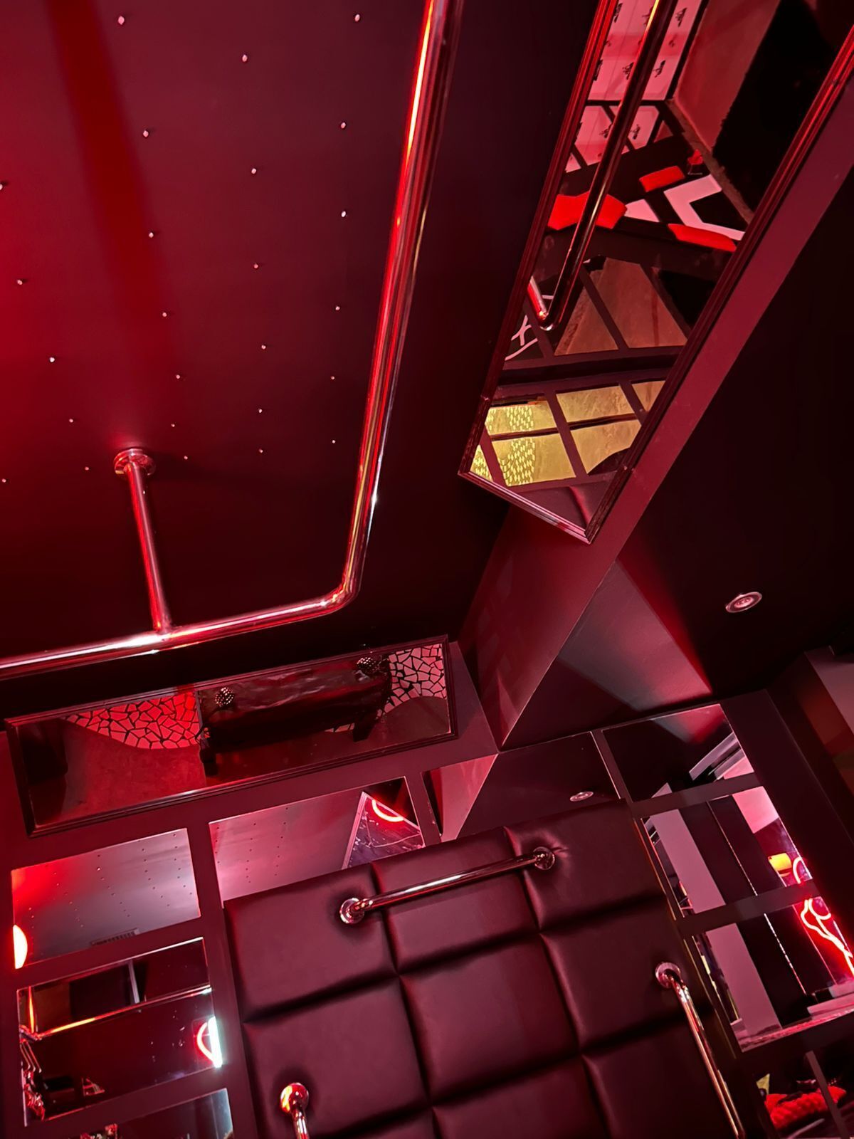 A modern interior with geometric design elements, reflective surfaces, and a red color scheme.
